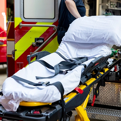 An empty stretcher or gurney against the open rear doors of an ambulance.