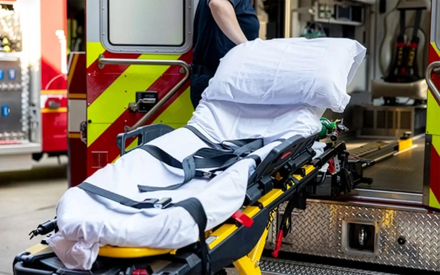 An empty gurney at the open rear doors of an ambulance.