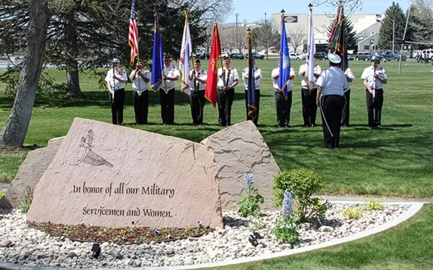 VFW Color Guard with a stone monument to service men and women in the foreground.