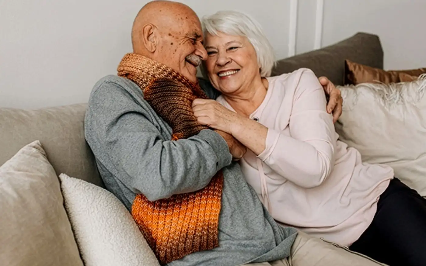Elderly couple embracing on a couch.