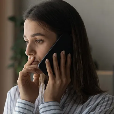 A woman with a worried expression on a cell phone.